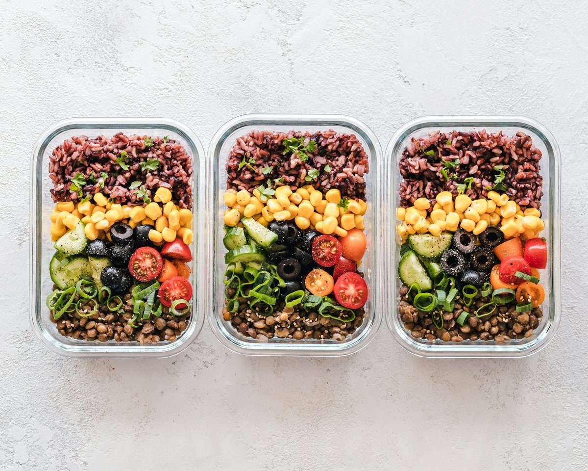 Trois boîtes en verre contenant des repas préparés à l'avance, avec des légumes et des féculents