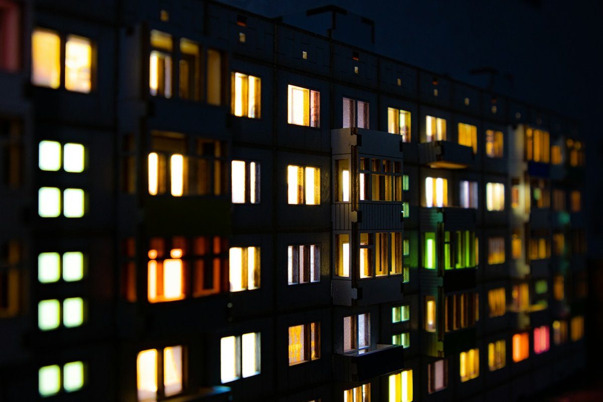Façade d'immeuble la nuit, fenêtres éclairées de couleurs différentes