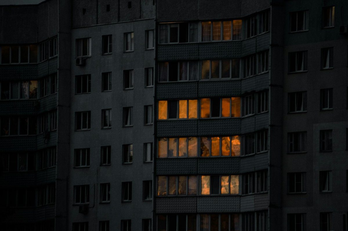 Façade d'immeuble la nuit avec quelques fenêtres allumées