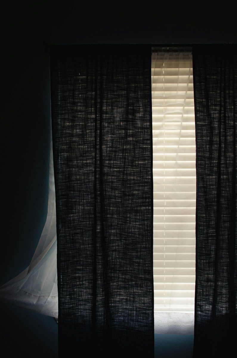 Rideau sombre tiré avec un rai de lumière sur le côté