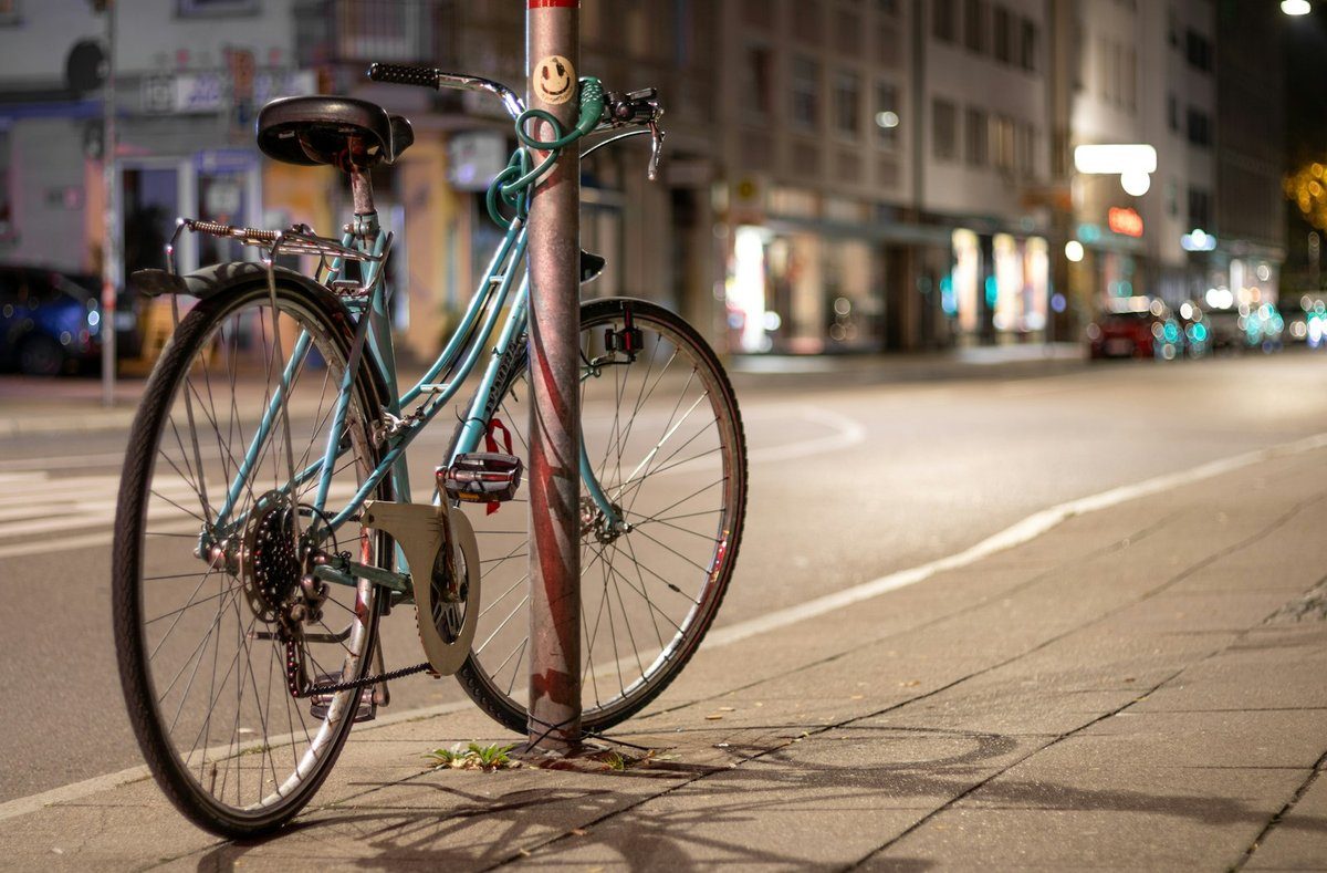 Vélo garé contre un poteau dans une rue éclairée la nuit