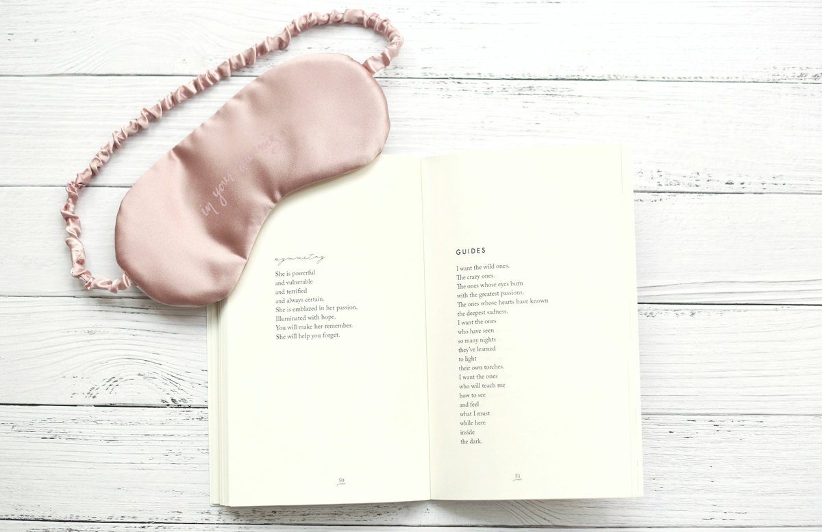 Masque de nuit posé sur un livre ouvert, prêt pour un coucher en journée
