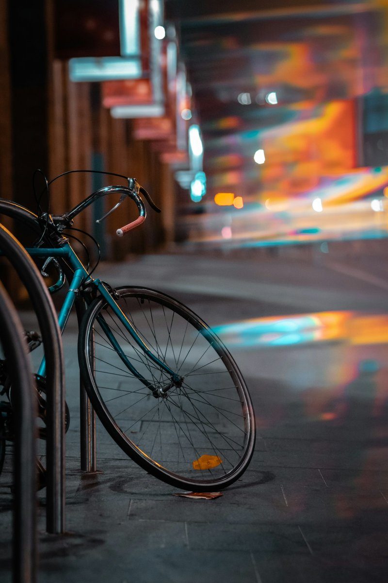 Vélo garé la nuit, lumières de la rue floues derrière